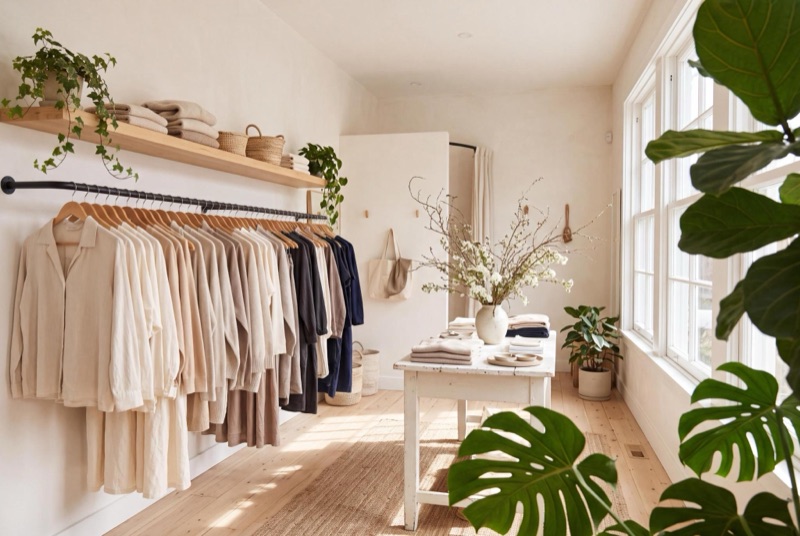Boutique rack of linen and knitwear beside a sunlit window